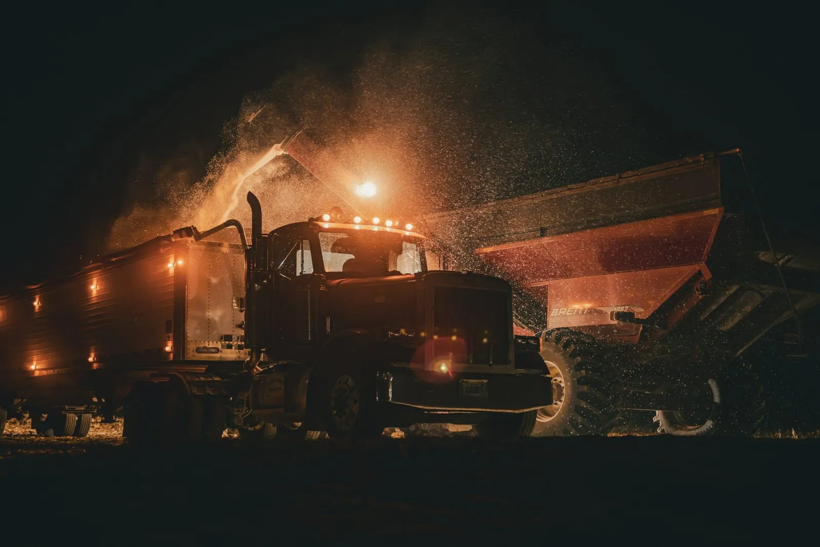 Heavy truck working at night, lit by its own floodlights amid dust