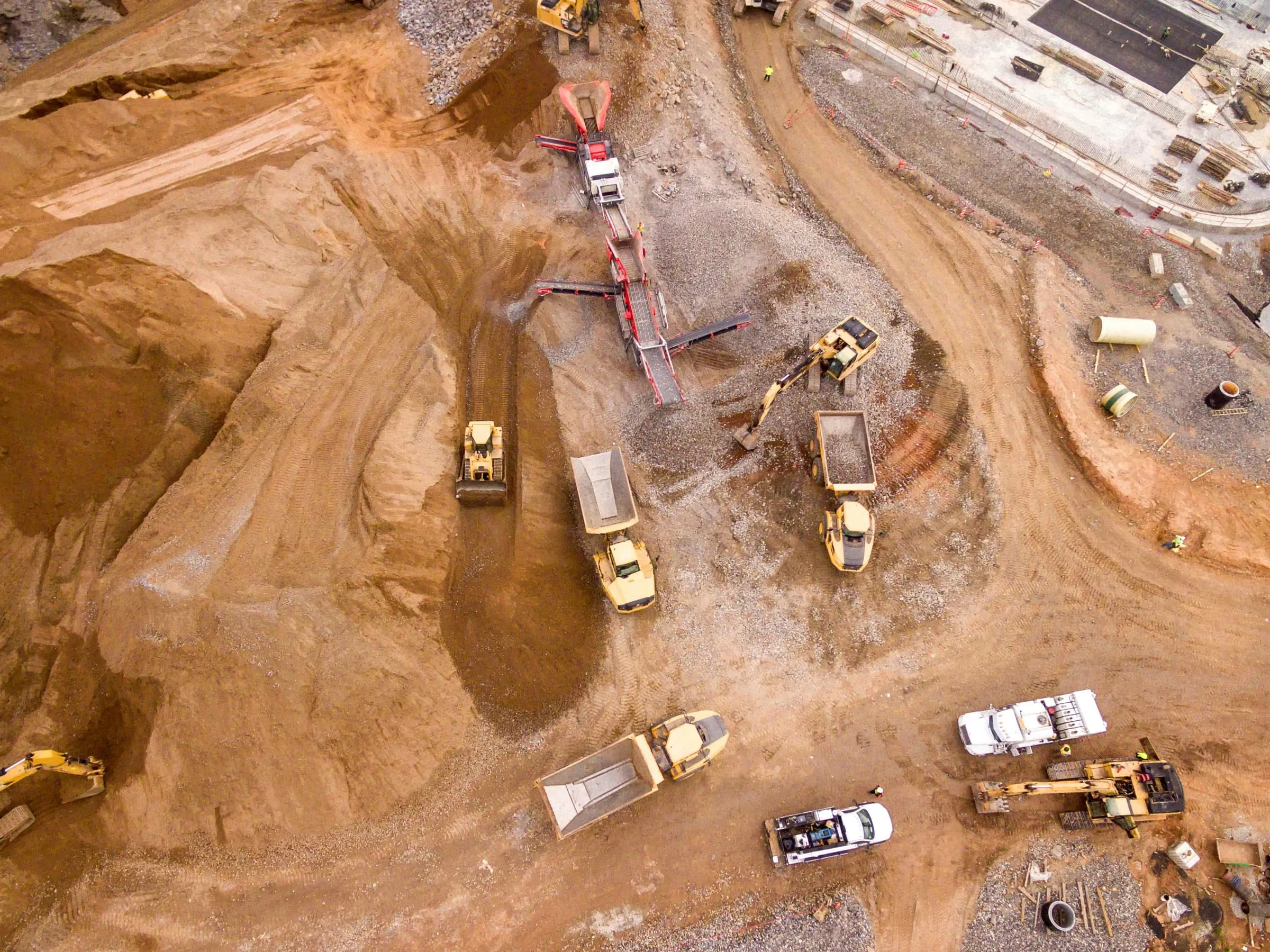 Aerial view of earthmoving machines and dump trucks working on a dusty construction site